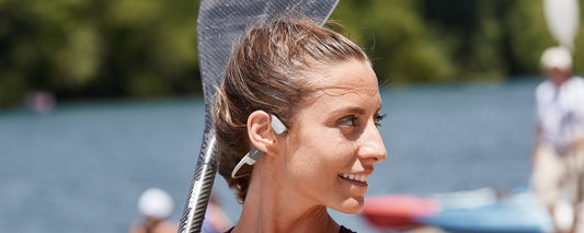 Woman kayaking while wearing AfterShokz Aeropex wireless headphones