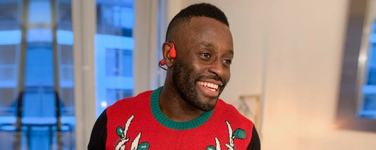 Man wearing Chritmas sweater and AfterShokz Aeropex wireless headphones