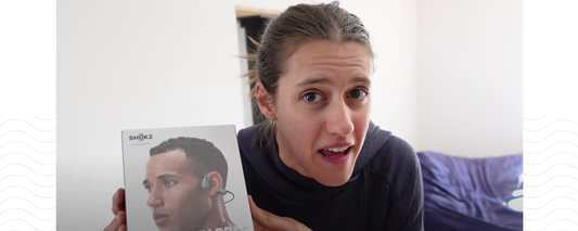 Professional mountain biker and YouTuber Syd holding a box of Shokz OpenRun Pro wireless sport headphones